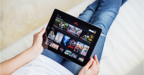 Image of person holding iPad streaming Netflix. 